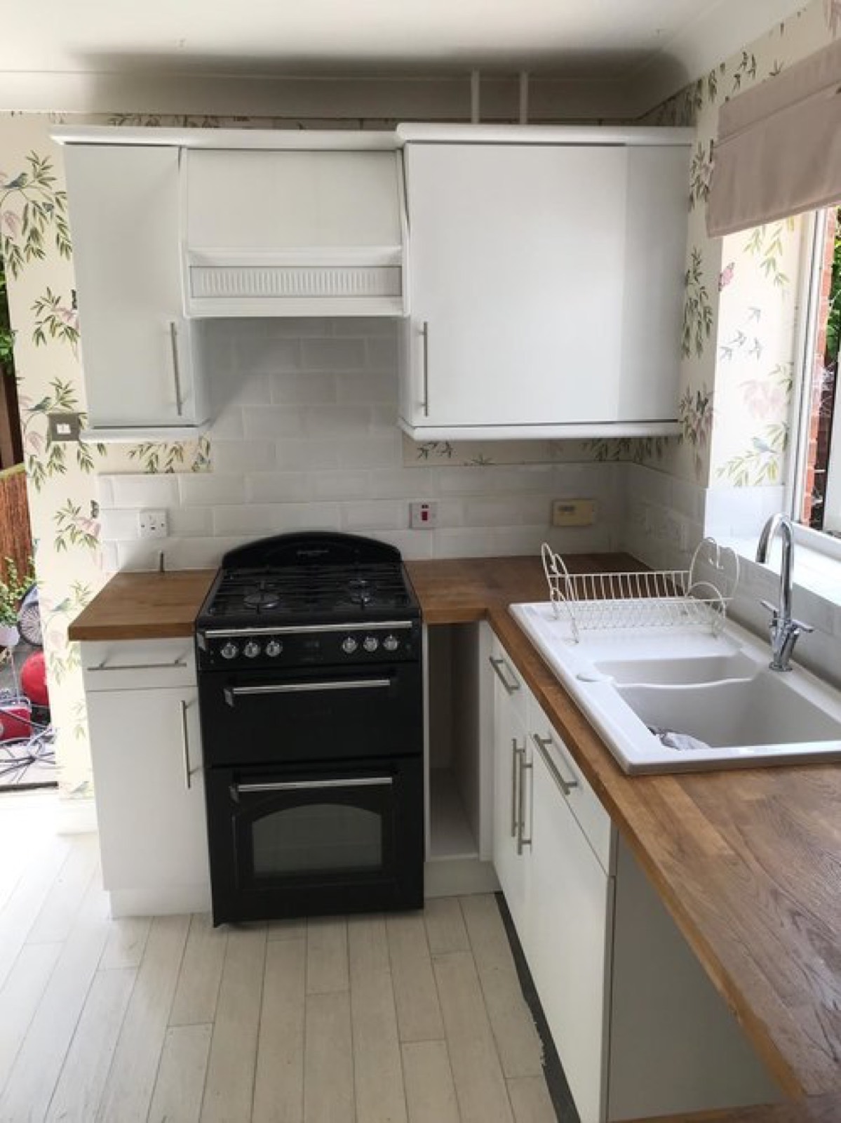 The same kitchen after its makeover with white sprayed units and canopy